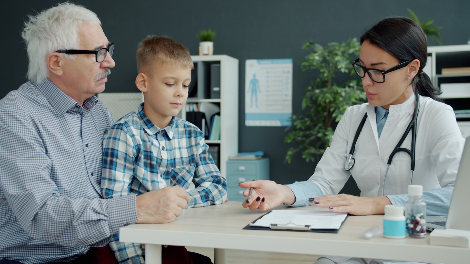 Doctor consults with grandfather and grandson in office, health